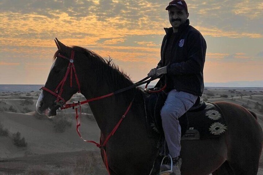 A person riding a horse in a desert landscape with a sunset in the background. 3