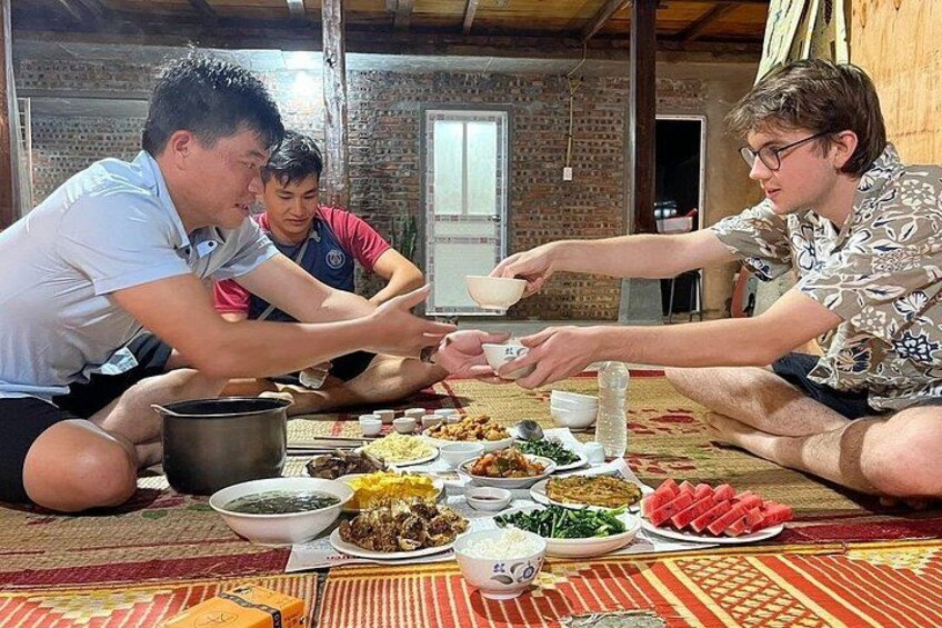 A group of people sitting on the floor around a table with various dishes. 2