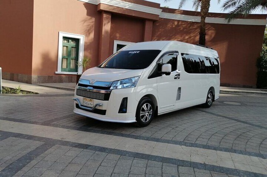 A white van parked in front of a building with a green door and windows. 3