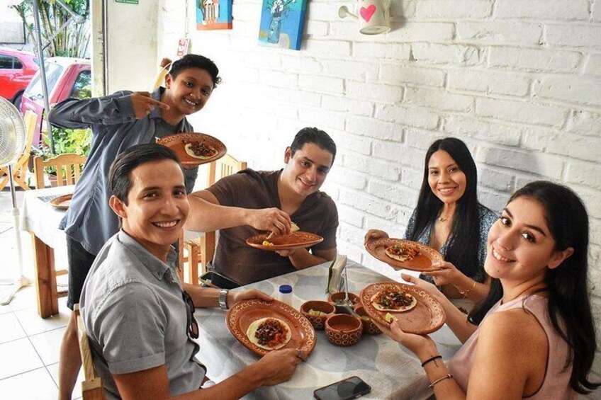 A group of people sitting around a table with traditional dishes and bowls. 2