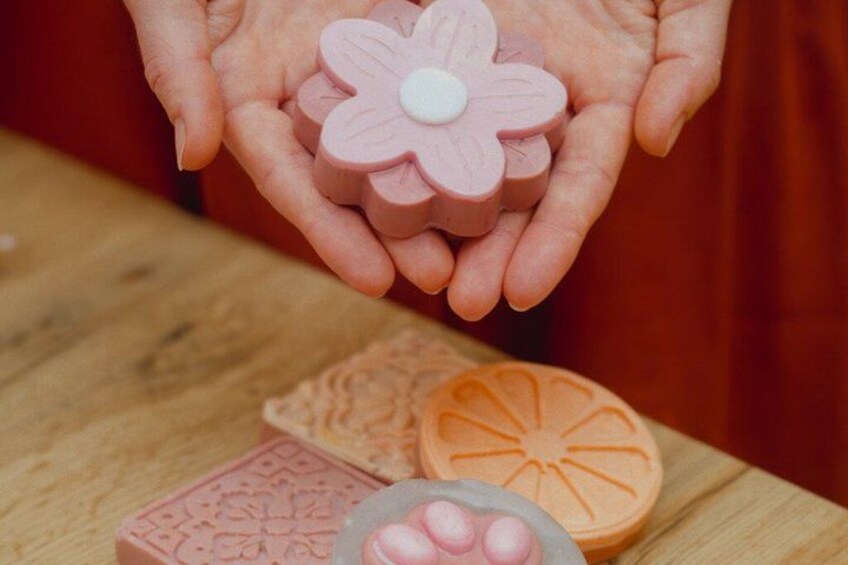 Une personne tient dans ses mains un savon rose en forme de fleur. 2