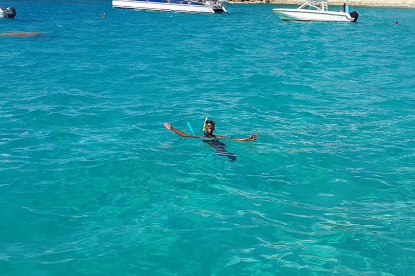 Una persona flotando en aguas turquesas cristalinas con barcos al fondo. 4