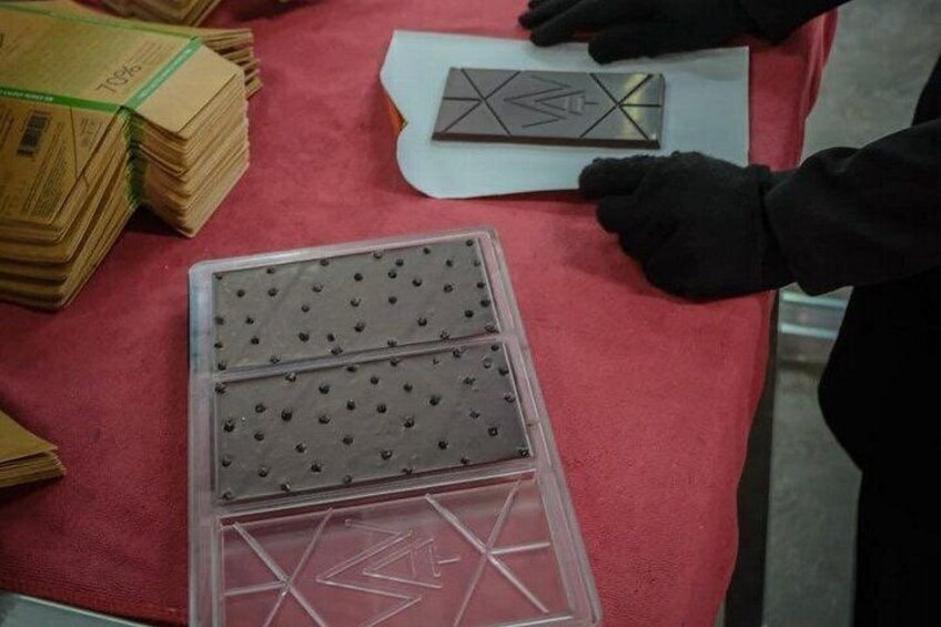 A person handling cardboard boxes and a plastic tray with a geometric pattern. 3