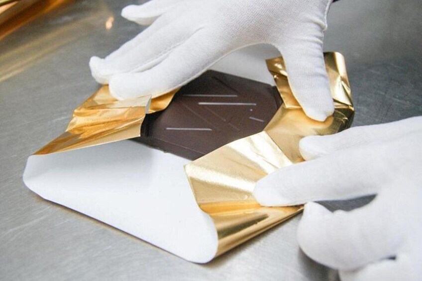 A person wearing white gloves handling a gold-colored object with a white base. 5