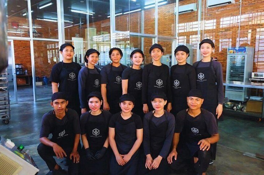 A group of people in a workshop setting with brick walls and industrial equipment. 2