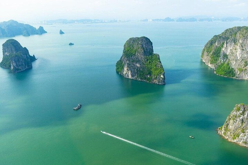 A coastal landscape with large limestone islands surrounded by calm, greenish-blue waters. 2