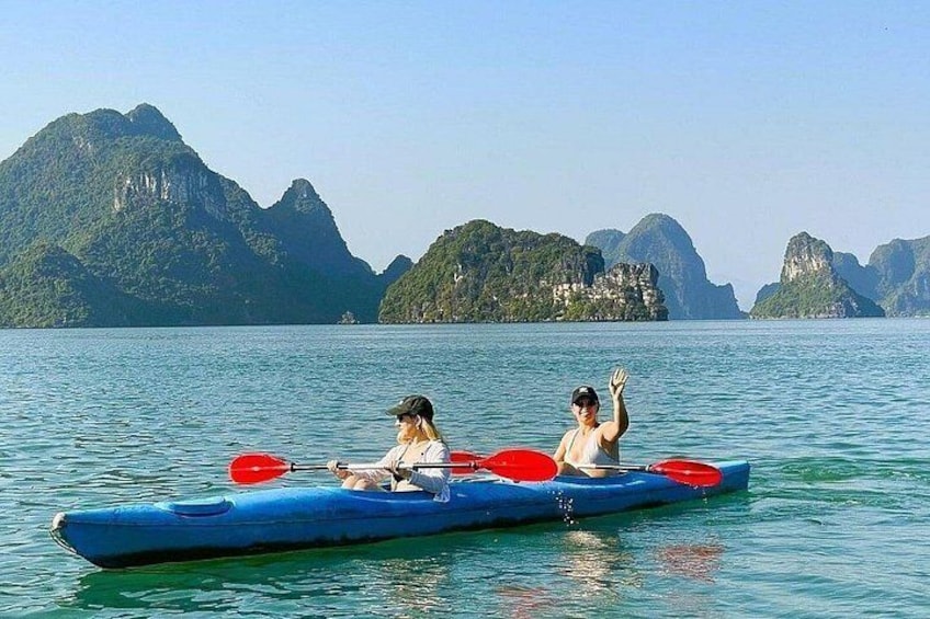 Two people kayaking on a calm body of water with mountainous terrain in the background. 1