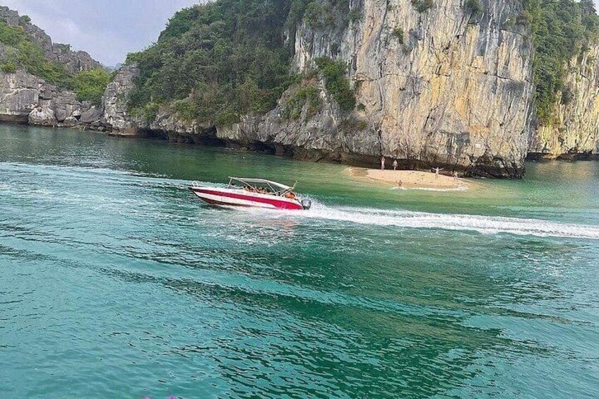 Una embarcación sobre aguas turquesas, una playa arenosa y acantilados rocosos. 4
