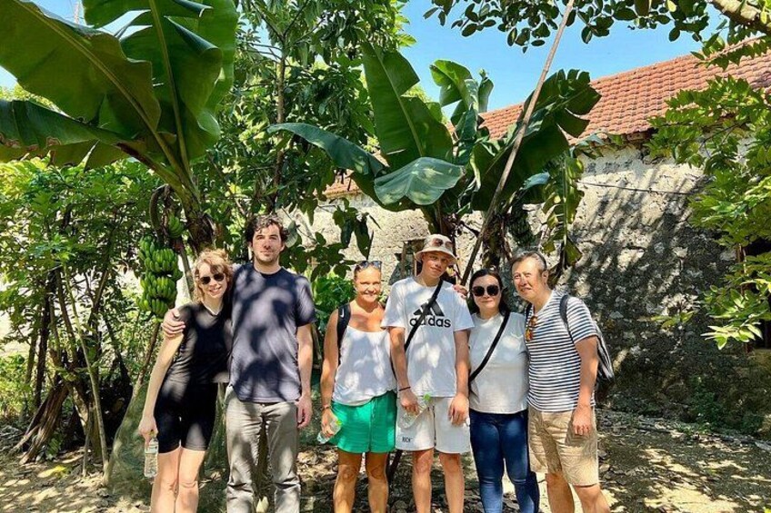 Un gruppo di persone in piedi all'aperto, con alberi e un edificio sullo sfondo. 5