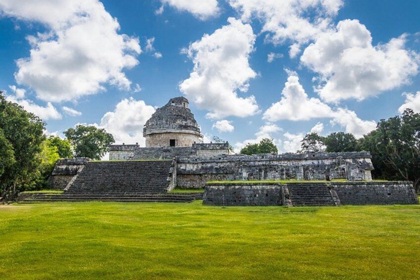 A large ancient pyramid with a stepped structure and a smaller dome-shaped building in the background. 3