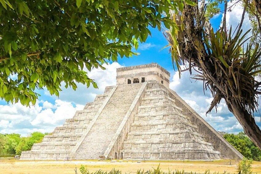 A large pyramid structure with a flat top, surrounded by greenery and a clear sky. 5