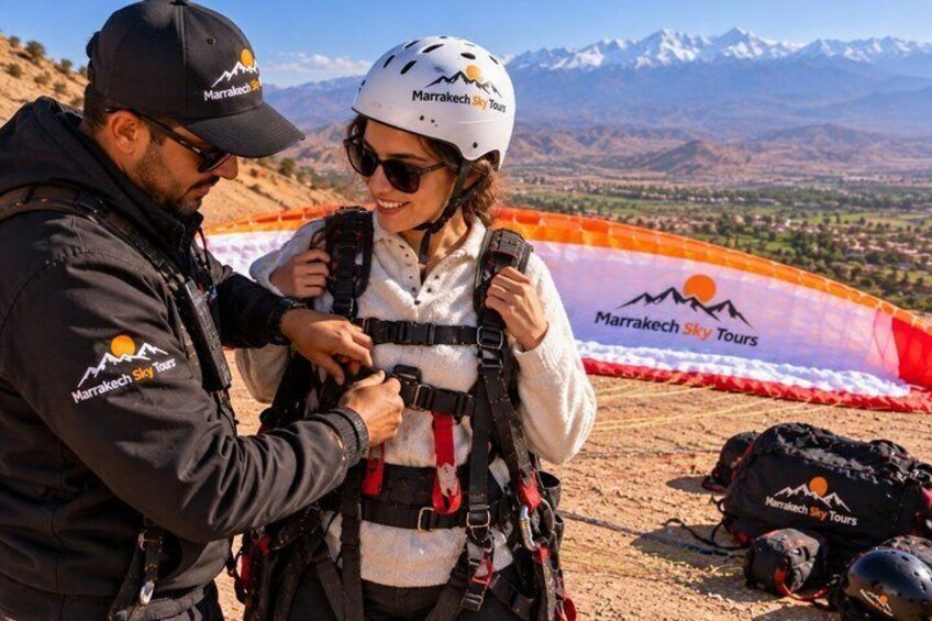 Two people preparing for a sky tour with a parachute and mountainous landscape in the background. 4