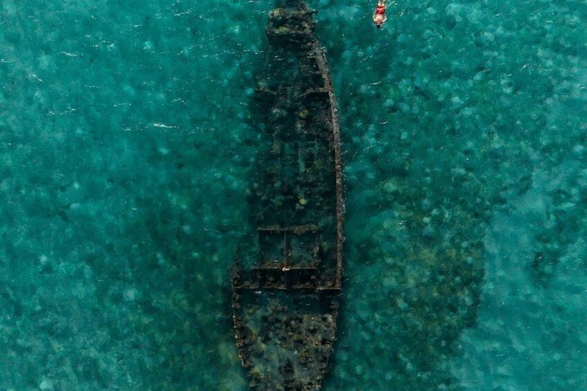 An aerial view of a shipwreck in clear turquoise waters. 2