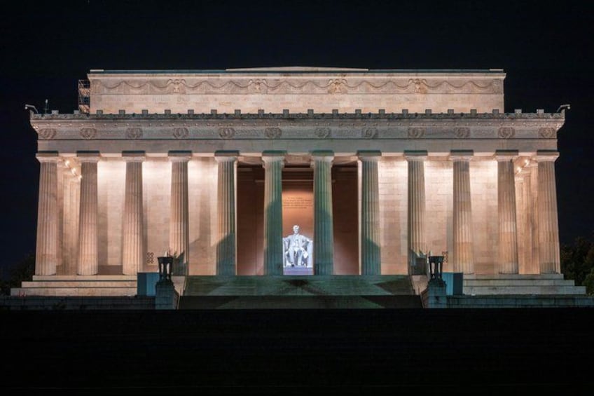 The Lincoln Memorial at night with a large screen displaying a figure. 2
