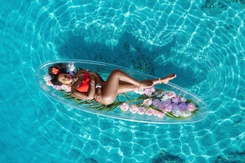 A person floating on a clear blue pool with a floral arrangement. 2