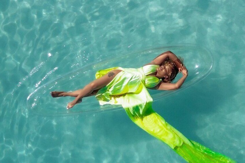 A person floating on a green inflatable tube in a clear blue pool. 5