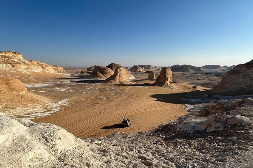 A desert landscape with sand dunes, rocky formations, and a clear sky. 1