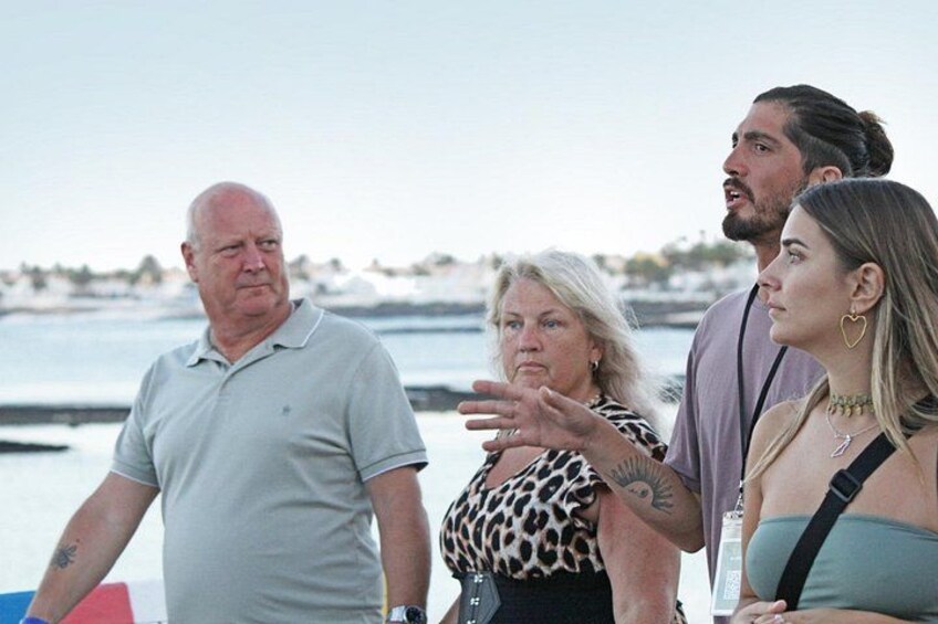 A group of people standing by a body of water with a distant shoreline. 3