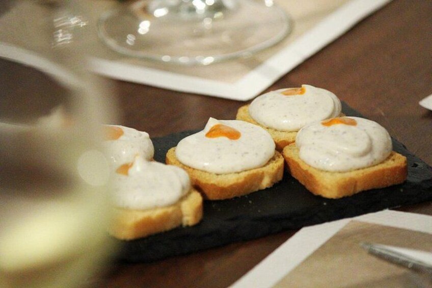 A plate of food with a creamy topping, a glass of white wine, and a napkin on a table. 4