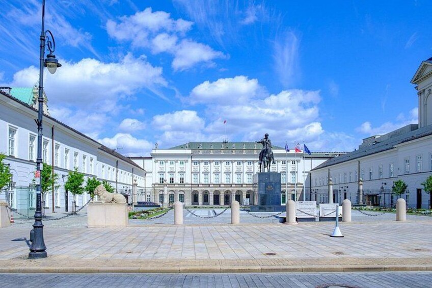 A square with a statue, buildings, and a clear sky. 5