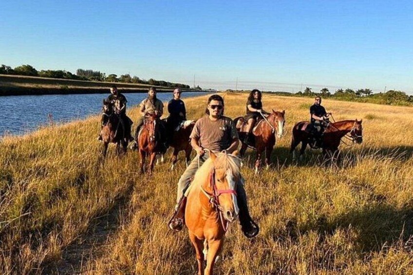 Een groep mensen te paard nabij een waterpartij. 5