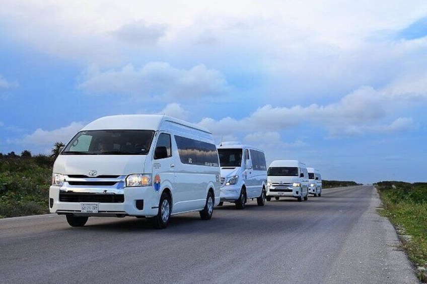 Una caravana de furgonetas blancas circulando por una carretera bajo un cielo despejado. 1