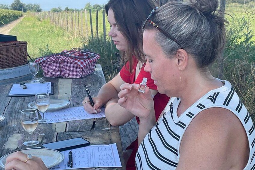 Two people at an outdoor table with wine glasses, a notebook, and a pen. 3