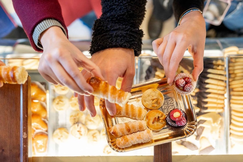 A person selecting pastries from a display case. 1