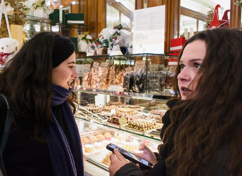 Two people in a bakery, one holding a smartphone. 2