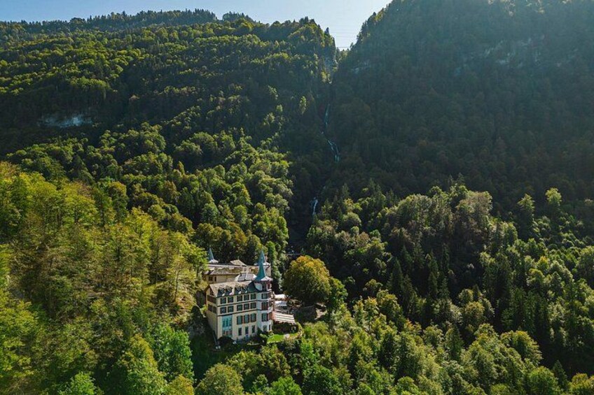 A house surrounded by dense forest and a waterfall. 2