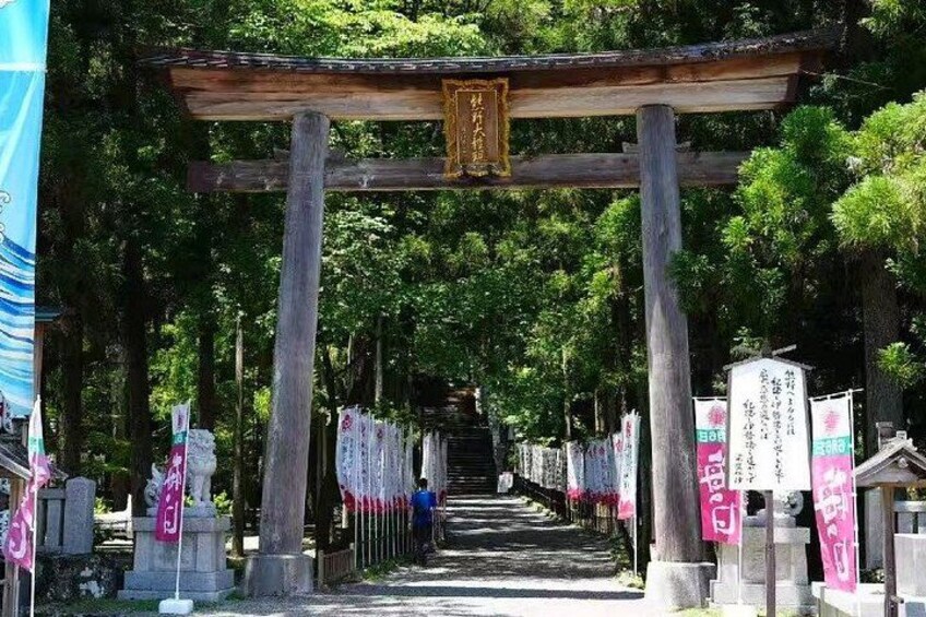 A traditional Japanese torii gate leading to a shrine, surrounded by trees and stone lanterns. 3