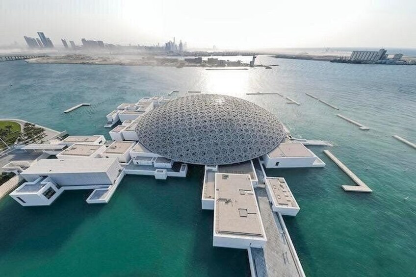 Vue aérienne d’une structure architecturale moderne au design circulaire, reliée à une zone riveraine par des promenades. 1
