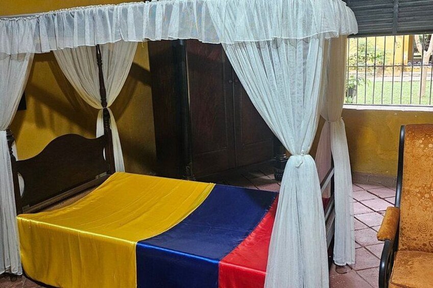 A bed with a yellow and blue bedspread, a white canopy, and a wooden headboard. 2