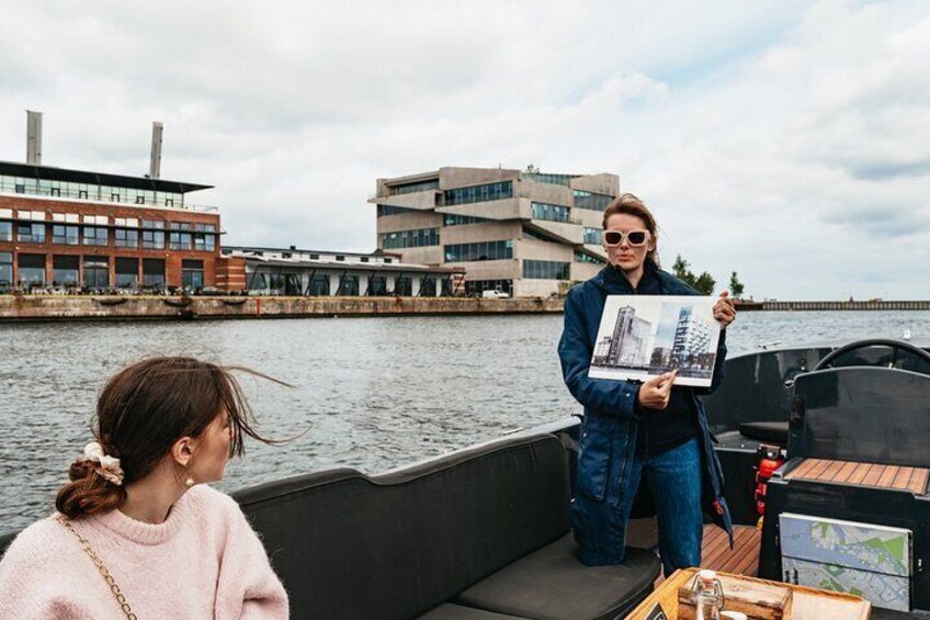 Eine Person hält eine Karte auf einem Boot, im Hintergrund sind Gebäude zu sehen. 5