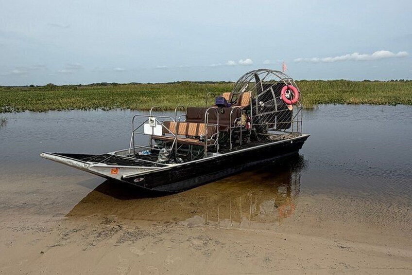 A boat with a canopy and life preserver on a muddy shore. 4