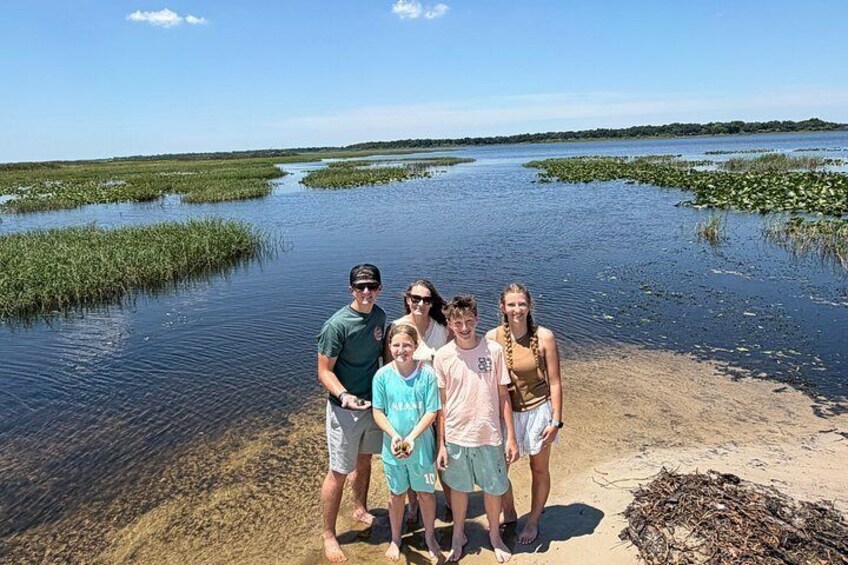 A group of people standing by a water body with vegetation in the background. 5