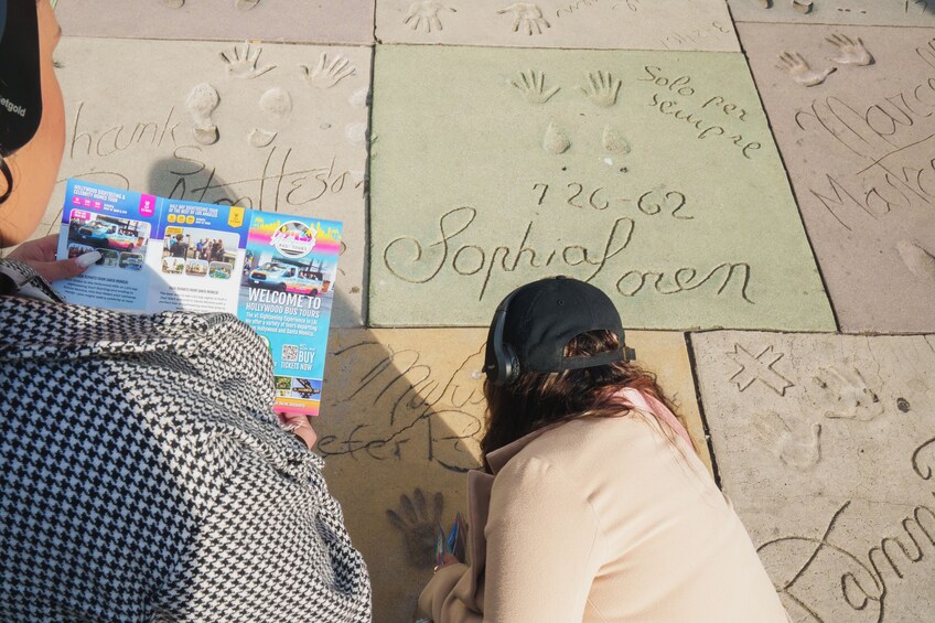 A person reading a brochure on the ground with handprints and names like "Sophia" and "Marcos" around. 5
