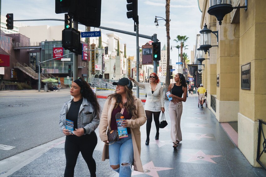 A group of people walking on a street with a Hollywood Walk of Fame star. 1