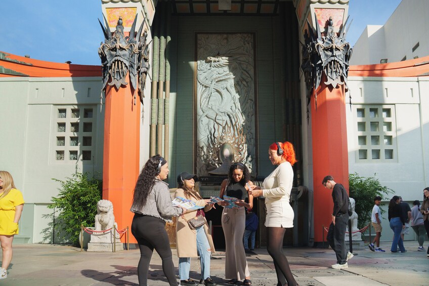 A group of people standing in front of a building with ornate columns and a large dragon relief. 4