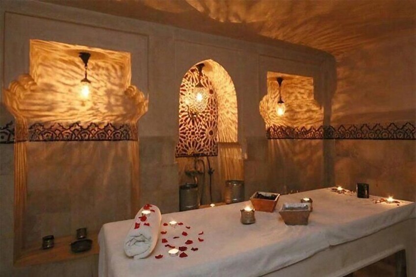 A spa room with a massage table, candles, and decorative wall panels. 2