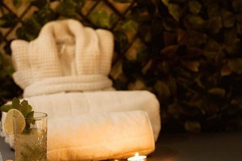 A cozy indoor setting with a white bathrobe, a glass of iced tea with a lemon slice, and a lit candle on a table. 4