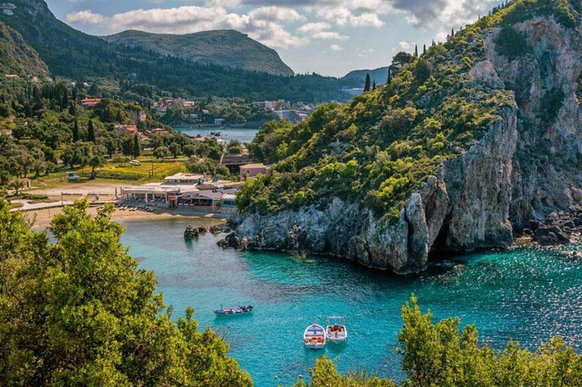 A coastal landscape with clear turquoise waters, rocky cliffs, and lush greenery. 4