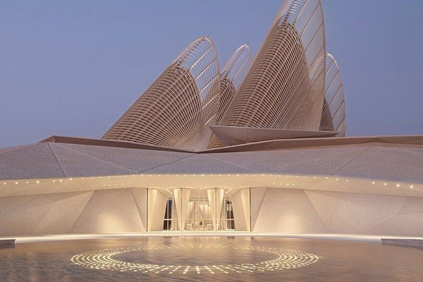 A modern architectural structure with a unique roof design and a circular pattern on the ground. 3