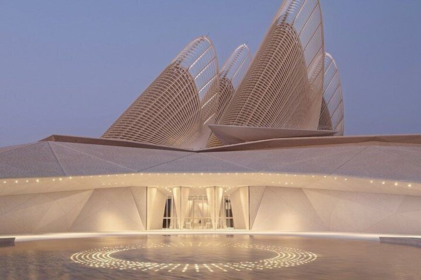 A modern architectural structure with a unique roof design and a circular pattern on the ground. 2