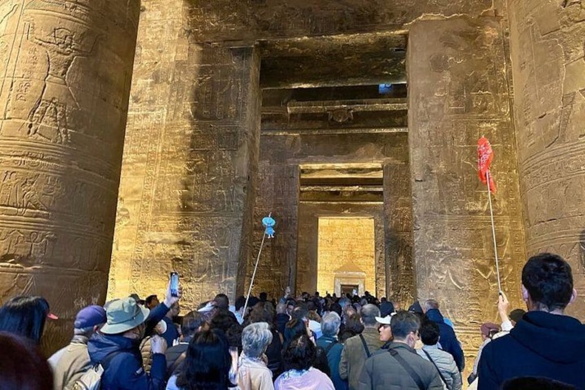 En folkmassa samlad vid ett forntida egyptiskt tempel, där väggarna är täckta av hieroglyfer. 5