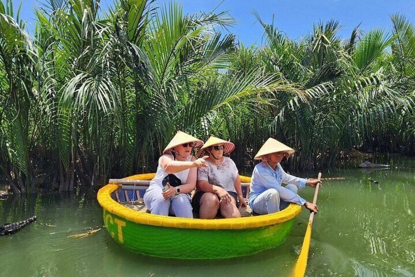 A green boat with three people wearing straw hats, paddling through a waterway surrounded by tall palm trees. 4
