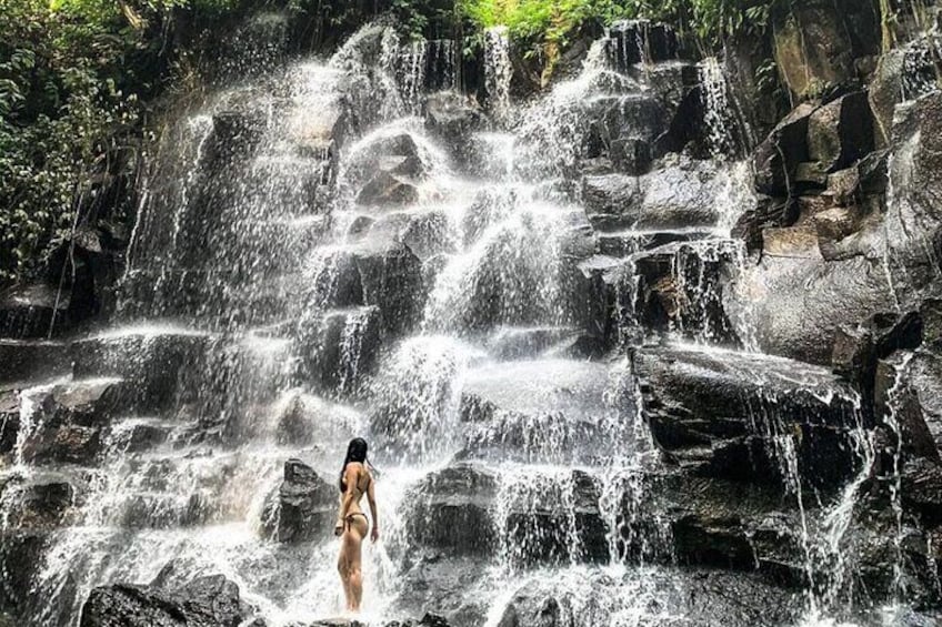 Ein Wasserfall, in dessen Wasser eine Person steht. 1