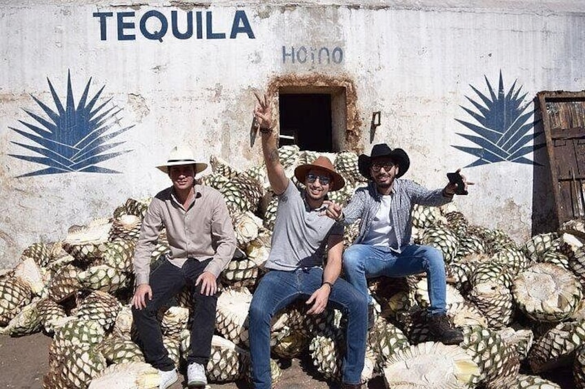 Tre mænd sidder på ananas foran en bygning med et tequila-logo. 3
