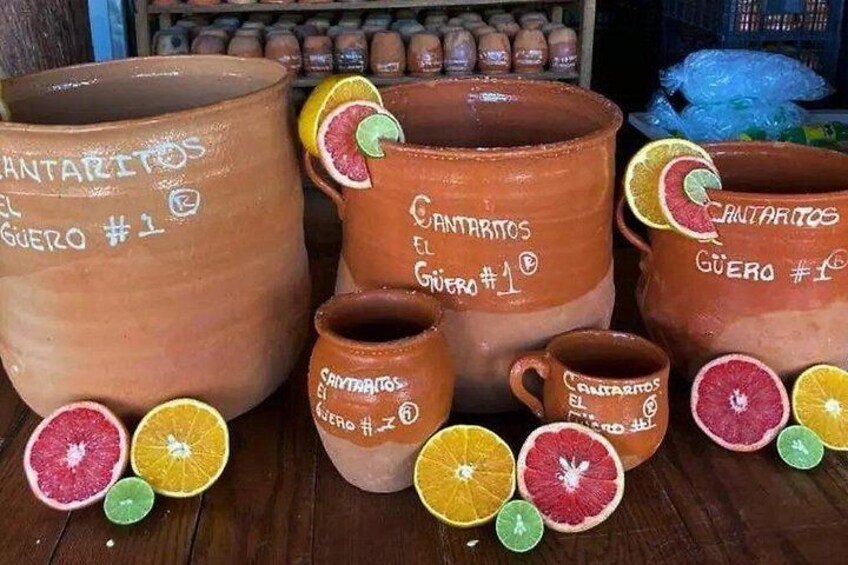 En samling keramik med teksten 'CANTARITOS' og 'GUERO #1', ledsaget af skivede citrusfrugter. 2
