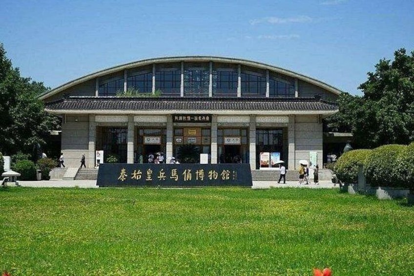 A large building with a curved roof and multiple windows. In front of the building, there is a sign with Chinese characters. 5
